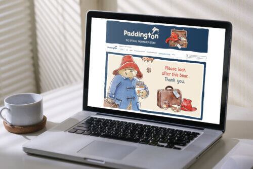 Laptop displaying the Paddington Bear Amazon storefront with character artwork and branded messaging.