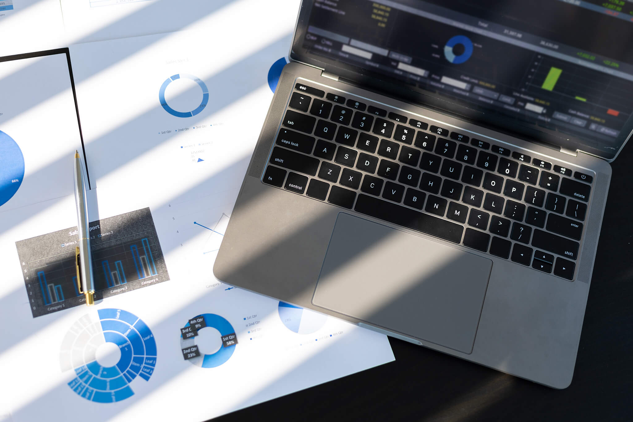 Laptop displaying analytics dashboard with printed charts and graphs showing Amazon sales performance data.