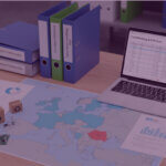 Desk with map of Europe, binders and a laptop showing cost data, representing Amazon EPR compliance planning.